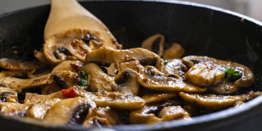 ahşap kürekler karıştırma ile bir Pan pişirme mantar ve kırmızı biber sosu