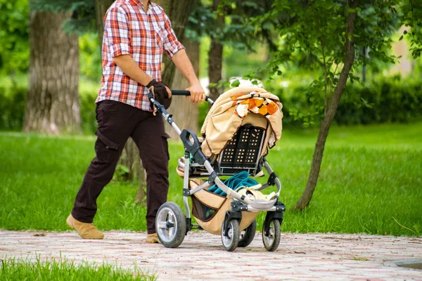 parents with baby carriage walking outdoor in the city street public park alleys