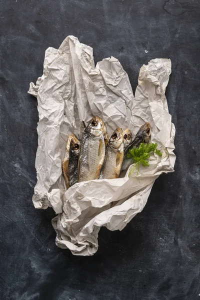 어두운 테이블에 베이킹 페이퍼에 허브와 향신료와 짠 신선한 튀긴 생선의 상단 보기 — 스톡 사진