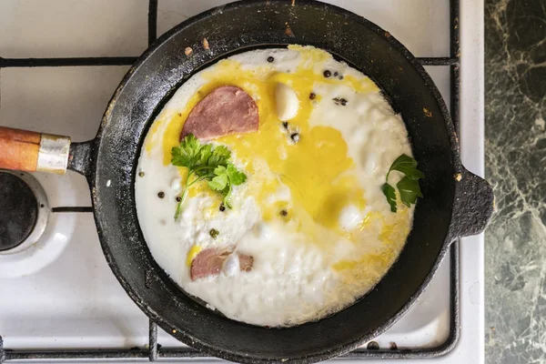 Закрыть процесс приготовления яиц в горячей сковороде с перцем и травами — стоковое фото