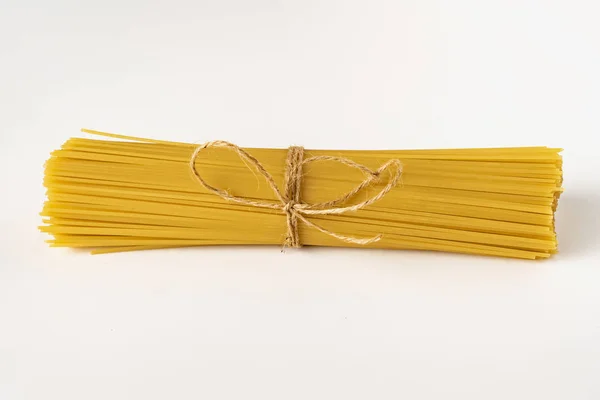 Provaz nebo svázaný svazek suché tepelně neupravené špagety izolované na bílém povrchu — Stock fotografie