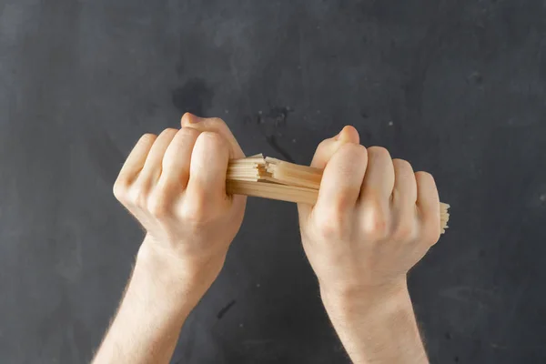 Visão em primeira pessoa de mãos masculinas quebrando um monte de espaguete isolado — Fotografia de Stock