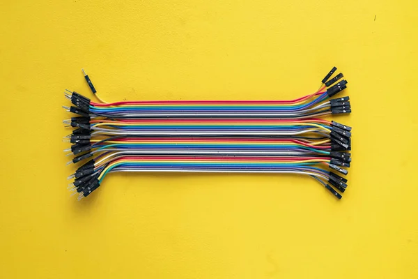 Monte de fios eletrônicos ou caples em isolamento colorido na mesa, conceito de conexão — Fotografia de Stock