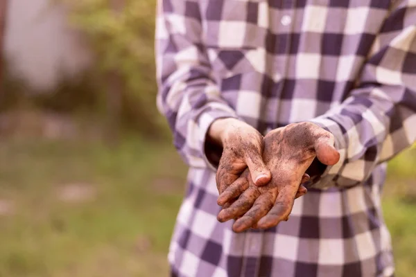 Dirty working farmer hands in soil standing in gardens — Stock Photo, Image