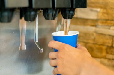 el bir fastfood restoranlarda limonata soda meşrubat makinesi dökmek için bir kağıt cam tutarak