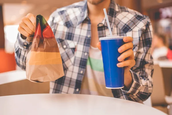 Человек держит пакет быстрого питания и стакан с обедом в общественных местах — стоковое фото