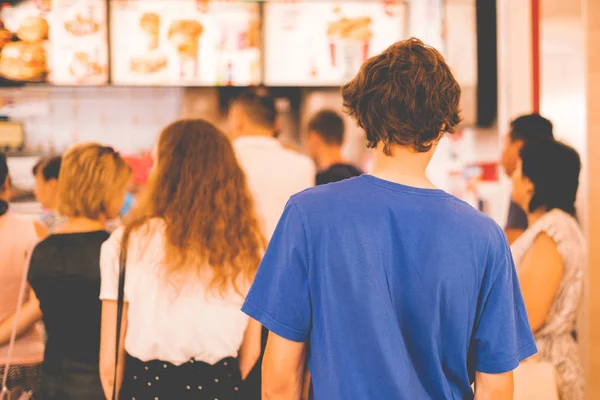Молодой подросток, стоящий в очереди за пакетами быстрого питания — стоковое фото