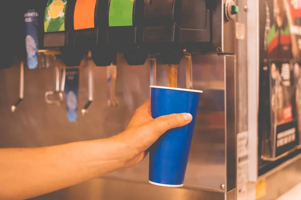 el bir fastfood restoranlarda limonata soda meşrubat makinesi dökmek için bir kağıt cam tutarak