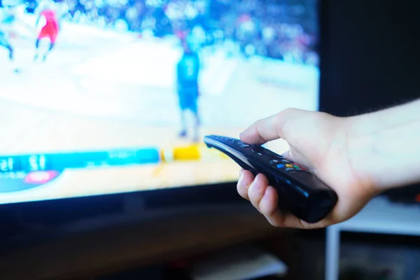 Mano sosteniendo un control remoto de televisión, girando pantallas de canales de medios — Foto de Stock