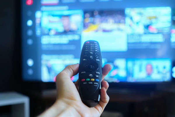 Mão segurando uma tv remota, swithing mídia chanels telas — Fotografia de Stock