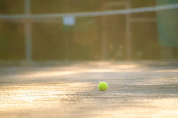 Cancha de tenis con pelota y red en un día de verano bajo los rayos del sol — Foto de Stock