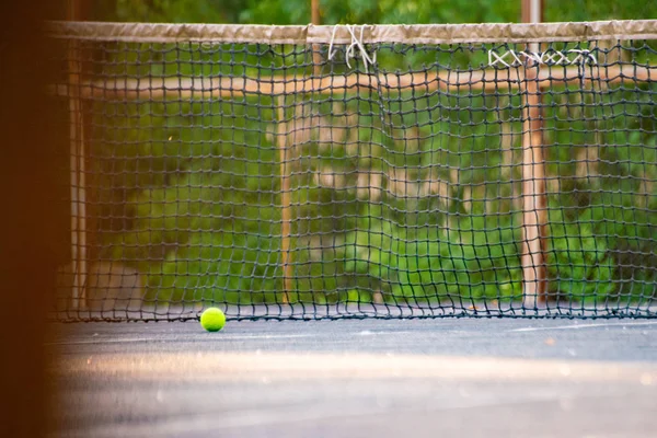 Cancha de tenis con pelota y red en un día de verano bajo los rayos del sol — Foto de Stock