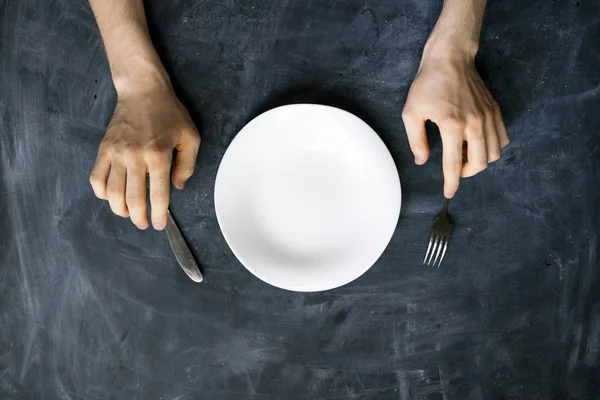 Top view of person's hands on the table with empty plate design mock up designs — Stock Photo, Image