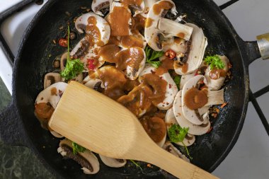 ahşap kürekler karıştırma ile bir Pan pişirme mantar ve kırmızı biber sosu