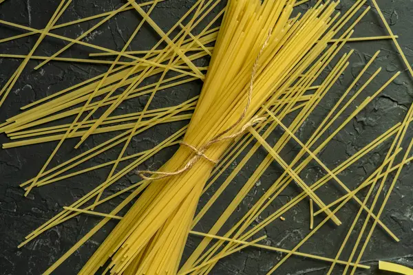 Купа сирих спагеті вид зверху, плоска лежала на темних поверхнях — стокове фото