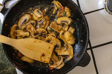 ahşap kürekler karıştırma ile bir Pan pişirme mantar ve kırmızı biber sosu