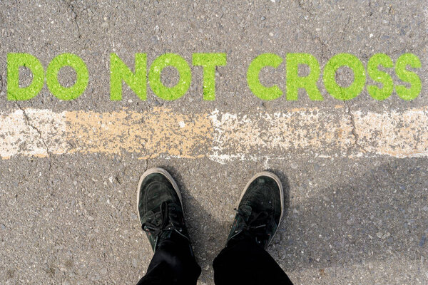 top down view of legs feet standing on the ground with don 't cross text concepts
