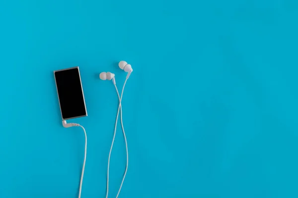 Disposición plana del dispositivo moderno reproductor de música y auriculares, concepto minimalista en las superficies de color — Foto de Stock
