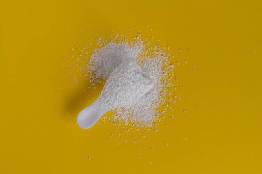 sarı yüzey üzerinde çamaşır tozu deterjanı ile küçük kepçe