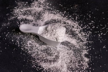 siyah yüzey üzerinde çamaşır tozu deterjanı ile küçük kepçe