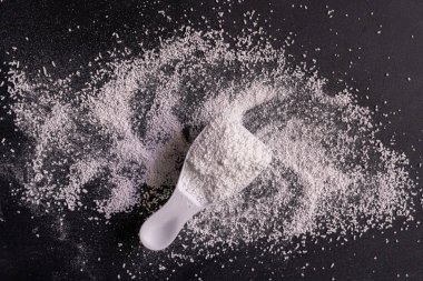 siyah yüzey üzerinde çamaşır tozu deterjanı ile küçük kepçe