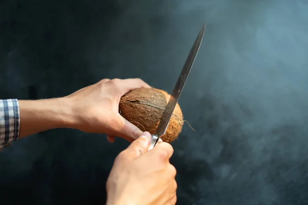 Людина з великим ножем намагається відкрити і розбити кокоси — стокове фото