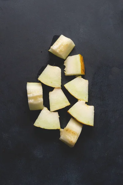 Vista superior de piezas cortadas en rodajas de melón fesh, cortadas en superficie negra — Foto de Stock