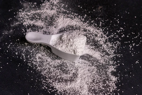 siyah yüzey üzerinde çamaşır tozu deterjanı ile küçük kepçe