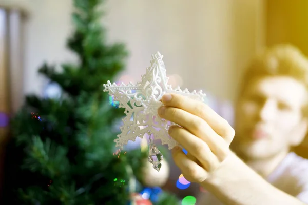 Fechar as mãos da pessoa colocando estrela decoração branca no topo da árvore de christmass f — Fotografia de Stock