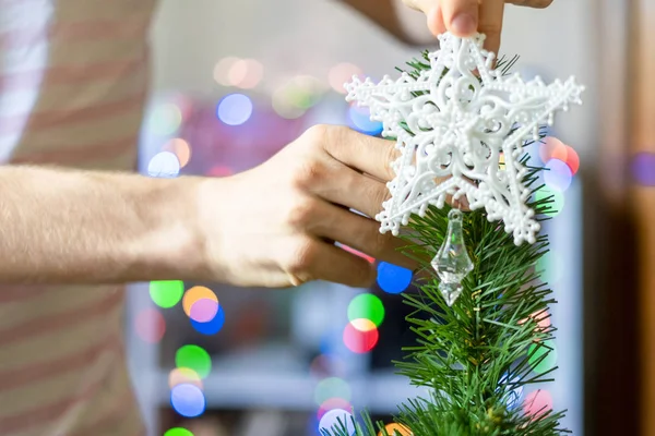 Fechar as mãos da pessoa colocando estrela decoração branca no topo da árvore de christmass f — Fotografia de Stock