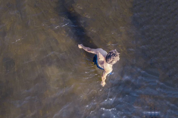 Topo viea aérea de homem jovem desfrutando de água do mar na praia, de pé no dia de verão — Fotografia de Stock