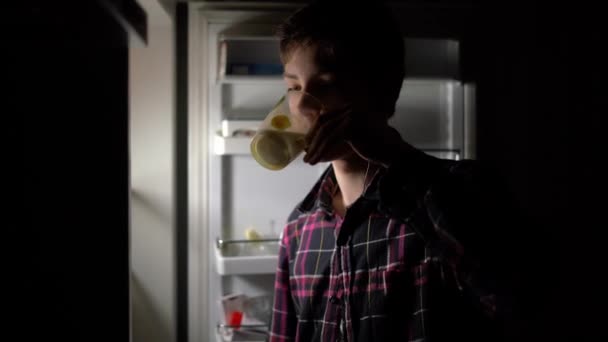 Attraktiver Teenager trinkt nachts kühle Milch aus dem Kühlschrank — Stockvideo
