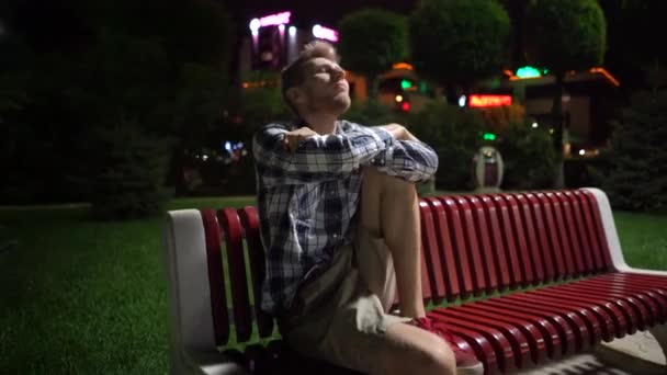 Flying shot of young man sitting on the bench, lost in the city — Stock Video