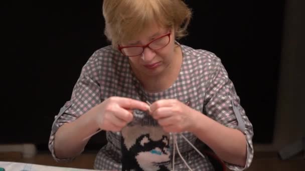 Femme au foyer chaussettes à coudre sur un fond sombre — Video