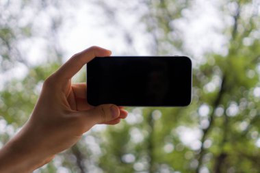 Kopya uzay dizaynlı siyah bir akıllı telefonu tutan el.