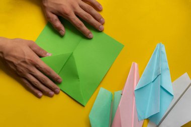 İnsan elleri origami renkli kağıt uçak yapıyor.