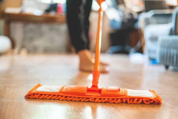 single man holding a mop and cleaning the laminate floor at home