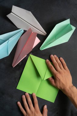 İnsan elleri origami renkli kağıt uçak yapıyor.