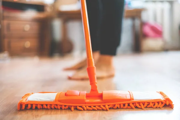 single man holding a mop and cleaning the laminate floor at home