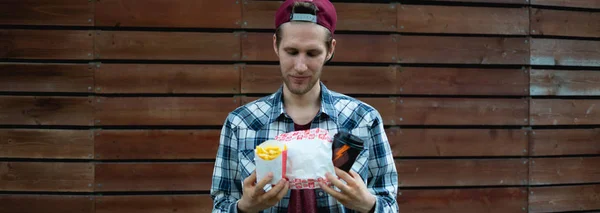 Persona con comida rápida en la calle durante el descanso diario con bebida, papas fritas y hamburguesas, sosteniendo en la mano —  Fotos de Stock
