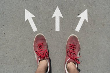 Nereye gideceğini seçmek zor, ayaklar asfalt yüzey oklarının üzerinde duruyor.