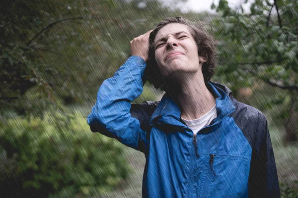 young man in wet clothes under pouring strong stormy rain