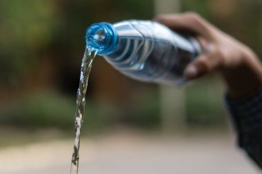 Elin plastik bir şişeyi tutuyor ve içinden su döküyor.