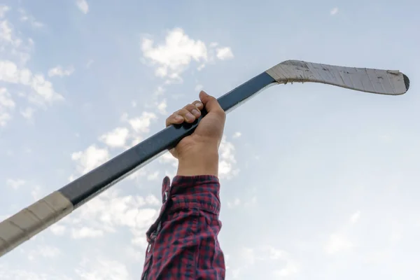 Main d'homme tenant un bâton de hockey contre le ciel, équipements sportifs abstraits — Photo