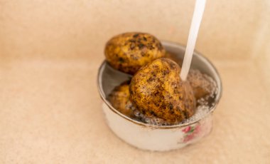 Patatesi pişirmek, kirli ham patatesi mutfakta suyla yıkamak.