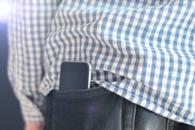 Erkek kıyafetlerinin cebindeki akıllı telefonu kapat, arka plan, cep telefonunun sağlık etkilerinin sembolü olarak.