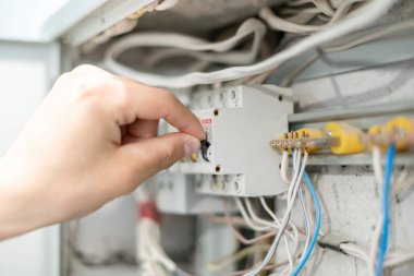 Profesyonel elektrik işçisi ev ışıklandırması sorununu çözüyor, güç panelini kaydırıyor.