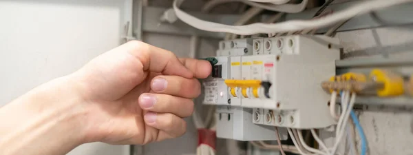 Profesyonel elektrik işçisi ev ışıklandırması sorununu çözüyor, güç panelini kaydırıyor.