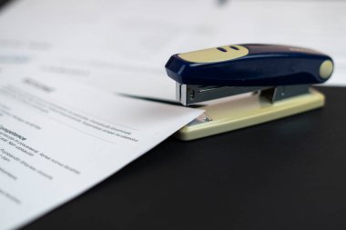 Zımba ve evrak dosyaları masanın üzerinde, özgeçmişin kağıt sayfalarını zımbalayın ve sözleşmeleri imzalayın.