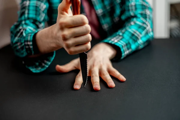 Kéz késsel üti az ujjak között az asztalon, játszani a játékot egy éles penge — Stock Fotó